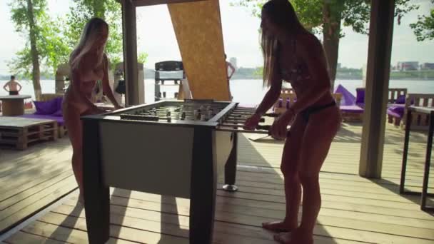 Donne che giocano a calcio balilla o kicker con giocatori in miniatura sulla spiaggia in costume da bagno — Video Stock