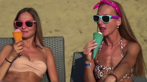 Mujeres jóvenes en trajes de baño, tomando el sol y comiendo helado en la playa — Vídeo de stock