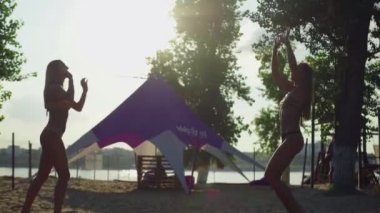 Güzel bir yaz akşamında plaj voleybolu oynayan neşeli genç kadınlar.