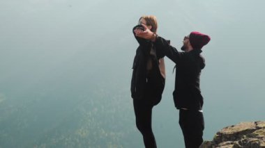 Genç bir çift turist bir dağ zirvesinde birlikte durup güzel manzaraya bakıyorlar. Doğada romantizm