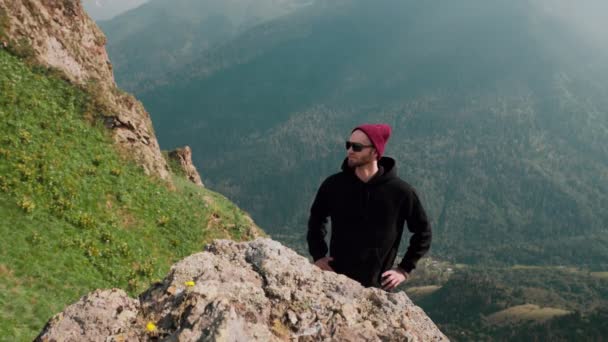 Mladý cestovatel, který stojí v horách a dívá se na nádhernou scenérii. Ten chlap stojí mezi krásnými horami. Cestovní ruch — Stock video