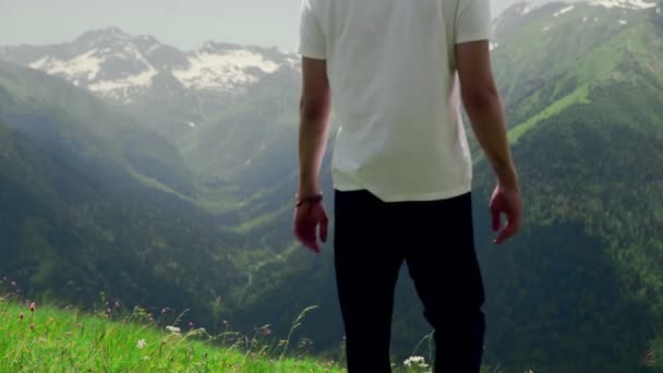 Arkadan bakınca genç bir adam yamaçtan aşağı yürüyor ve dağlık alanların muhteşem manzarasının tadını çıkarıyor. Turizm ve seyahat — Stok video