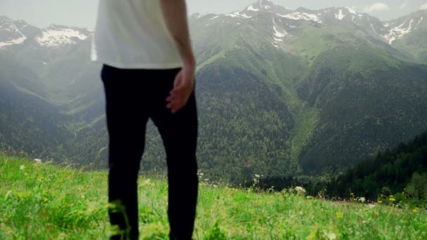 Arkadan bakınca genç bir adam yamaçtan aşağı yürüyor ve dağlık alanların muhteşem manzarasının tadını çıkarıyor. Turizm ve seyahat — Stok video