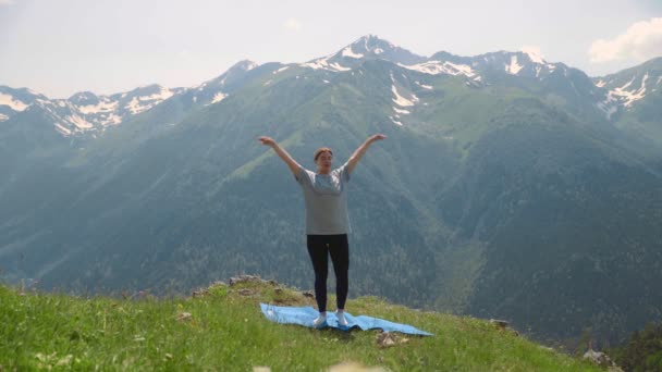 Una joven hace yoga en las cimas de las montañas. Turismo deportivo — Vídeos de Stock