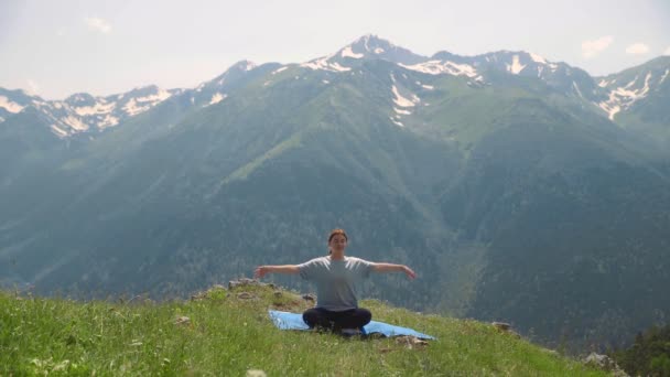 Een jonge vrouw doet yoga op de toppen van de bergen. Sporttoerisme — Stockvideo