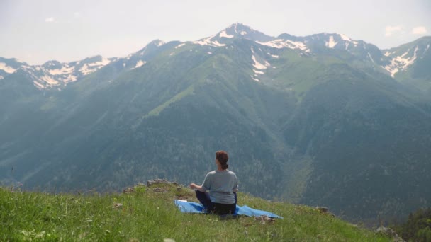 Una joven hace yoga en las cimas de las montañas. Turismo deportivo — Vídeos de Stock