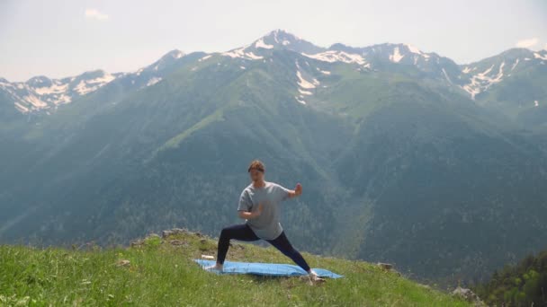Een jonge vrouw doet yoga op de toppen van de bergen. Sporttoerisme — Stockvideo