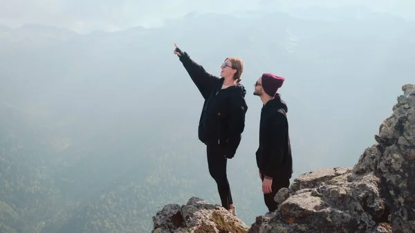 若いカップルの観光客が一緒に山の頂上に立って、美しい景色を見ている。自然の中でのロマンス — ストック写真