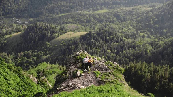 Uma jovem e um homem estão deitados em um penhasco em uma área montanhosa. Viagens — Fotografia de Stock