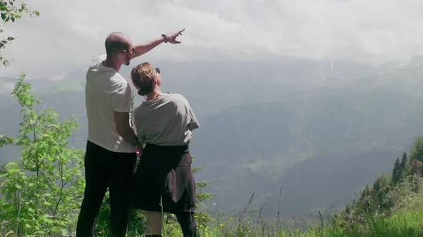 山間部の岩の上に若い男と女の子が立っていて、美しい風景を見ています。観光 — ストック写真