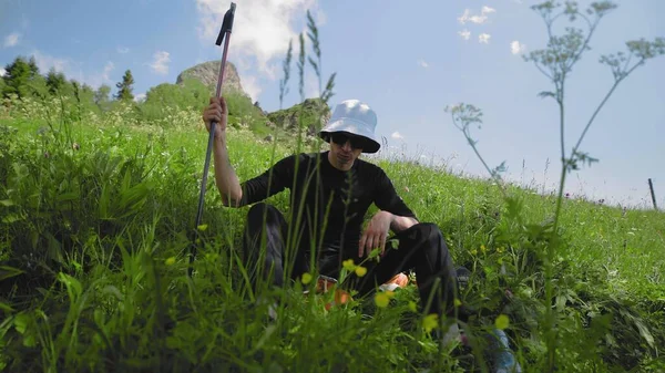 黒眼鏡の疲れた青年と白いパナマ帽が山の中腹に座っている。旅行・観光 — ストック写真