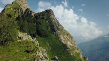 Dağlık bir bölgede bir kayanın üzerinde duran genç bir adam ve kadının kuşbakışı manzarasına hayran kaldım. Turizm
