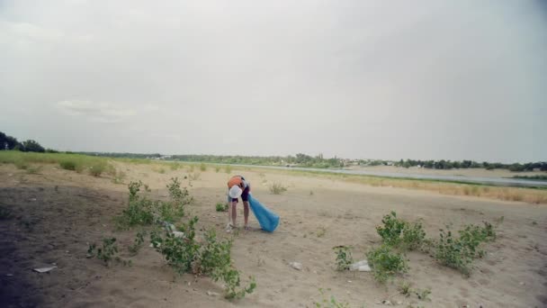 Egy férfi műanyaghulladékot gyűjt a parton. ökológia a környezetvédelem és a hulladék-újrafeldolgozás fogalma. Ökológia — Stock videók