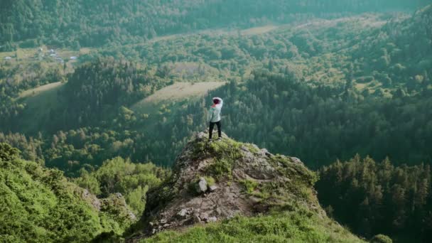Un joven está parado en un acantilado en las montañas. Viajes — Vídeo de stock