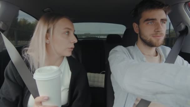 Un homme et une fille conduisent une voiture et boivent des boissons. Les gens conduisent en voiture. — Video