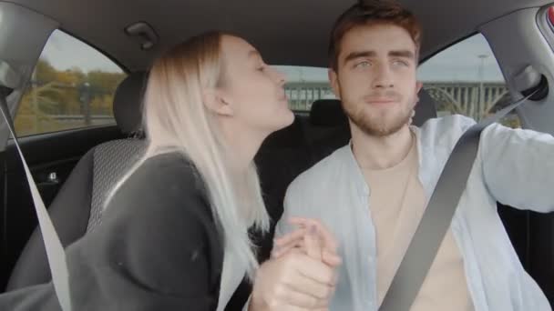Bir adam ve bir kız araba sürüyorlar. Kız partnerini yanağından öpüyor. İnsanlar araba kullanıyor. — Stok video