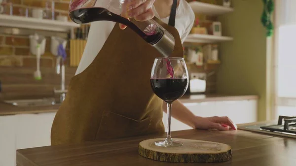 Een onherkenbare vrouw giet wijn uit een karaf in een prachtig glas. Close-up. — Stockfoto