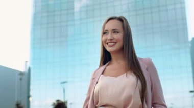 Elinde bir telefonla kameraya doğru yürüyen gülümseyen genç bir kadının yakın çekimi.