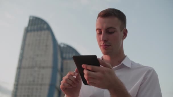 Un gars dans la rue le soir lit un e-book — Video