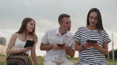 İki kız ve bir adam bütün gün parkta oturup e-kitap okuyorlar.