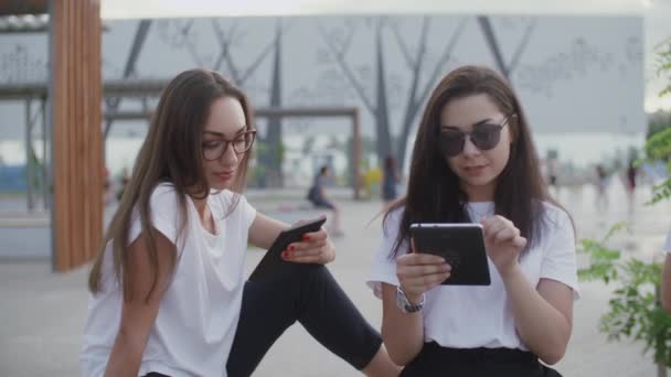 Duas meninas ao ar livre ler um e-book — Vídeo de Stock