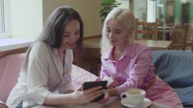 İki kız bir kafede oturup e-kitap okuyor.