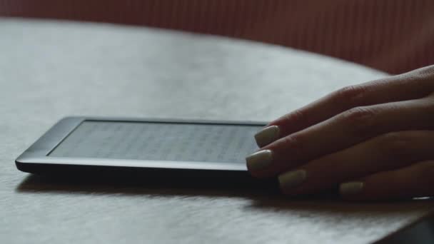 E-book στο τραπέζι με μια γυναίκα χέρι close-up — Αρχείο Βίντεο