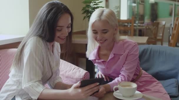 Dua gadis duduk di kafe dan membaca e-book — Stok Video