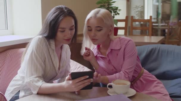 Дві дівчини сидять в кафе і читають електронну книгу — стокове відео