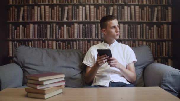 Der Typ in der Bibliothek liest ein E-Book — Stockvideo