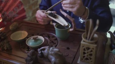 Çay dükkanındaki genç bir adam ahşap bir spatulaya çay yaprakları koyar.