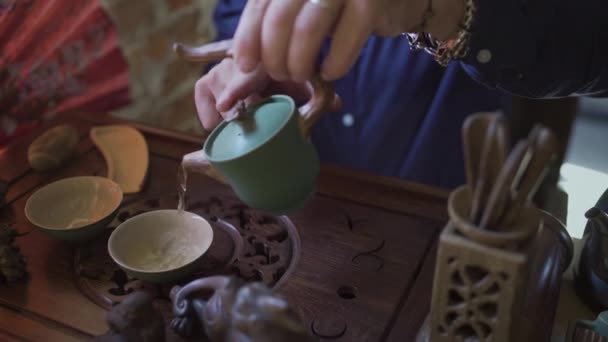 Un hombre vierte té en tazas de té en una bandeja de madera en una sala de té — Vídeo de stock