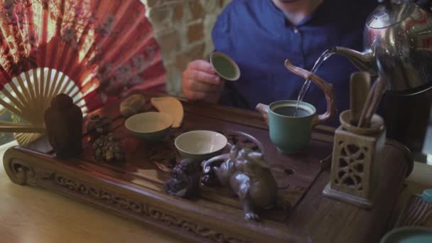 Un bărbat toarnă apă clocotită dintr-un ceainic într-un ceainic pentru prepararea ceaiului într-o cameră de ceai. — Videoclip de stoc