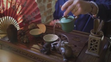 Bir adam çay bardaklarına çay koyar çay odasındaki ahşap tepside