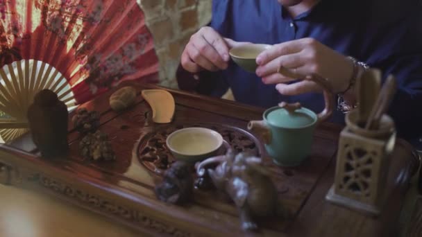 Un uomo beve tè verde da un set da tè in una sala da tè — Video Stock