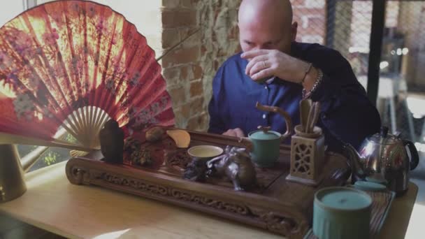 Um homem bebe chá verde de um conjunto de chá em uma sala de chá — Vídeo de Stock