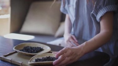 Güzel kıvırcık saçlı bir kız çay yaprakları ve kokularıyla tahta bir kase aldı.