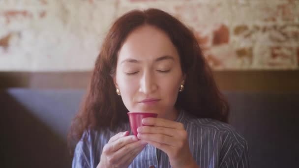 Een mooi krullend meisje proeft thee en geniet van de smaak — Stockvideo