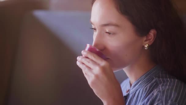 En vacker lockig flicka smakar te och njuter av smaken — Stockvideo