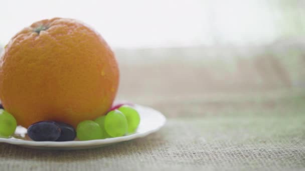 Orange and grapes on a plate, close-up — Stock Video
