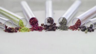 Masanın üzerinde yedi test tüpü var ve her birinde farklı baharatlar ve baharatlar var.