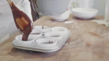Aşçı çikolatayı mutfak masasındaki kek kalıplarına döküyor.