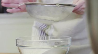 Mutfakta bir kız cam bir kaseye un döküyor.