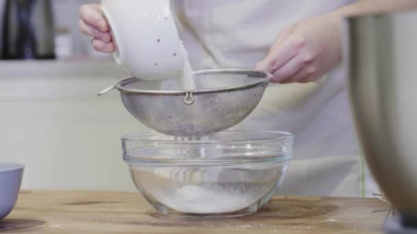 Uma menina na cozinha derrama farinha em uma tigela de vidro close-up — Vídeo de Stock