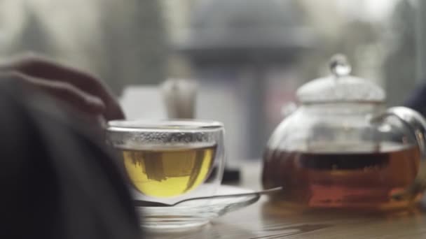 Мужская рука берет стакан с зеленым чаем в руке — стоковое видео
