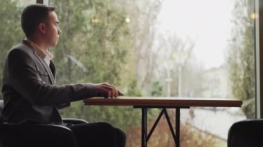 Restoran masasında elinde telefonla oturan bir adam.