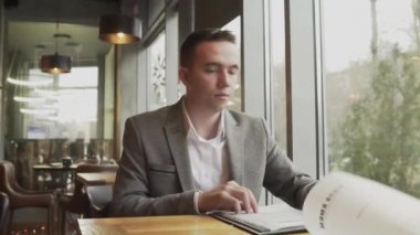 Bir erkek ve bir kadın menüden bir yemek seçiyorlar, pencerenin yanındaki bir kafede karşılıklı oturuyorlar. Hoş bir çiftin randevusu var..