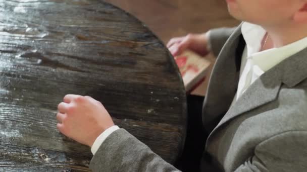 Un uomo prende una confezione regalo da sotto il tavolo e la mette sul tavolo in un caffè o in un ristorante primo piano — Video Stock