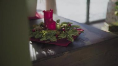 İki kırmızı mum ve bir altın mumu olan ebedi yeşil bir çelenk. Noel arifesinde Hıristiyanların gelenek ve adetleri.