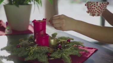 Tanınmayan bir kız, iki kırmızı mum ve bir altın mumla her daim yeşil bir çelenk yakar. Noel arifesinde Hıristiyanların gelenek ve adetleri. Bayramın sembolü..